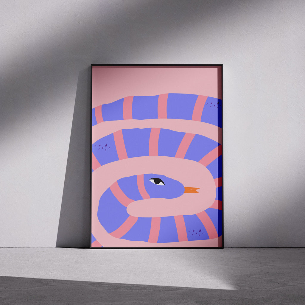 Framed abstract artwork with a snake design on a pink background, leaning against a gray wall.